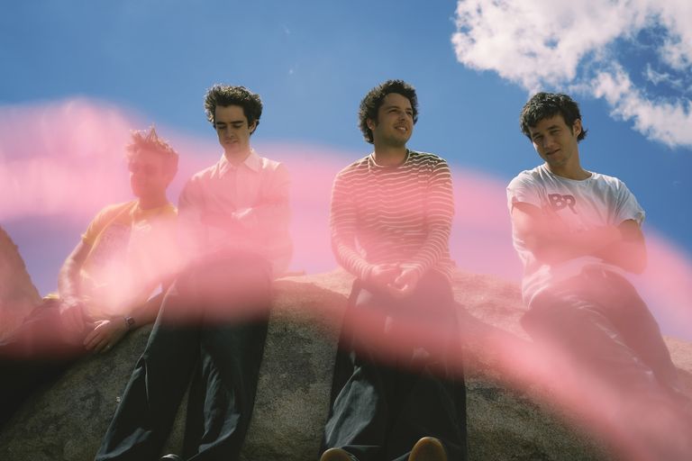 Promotional portrait of Australian post-punk band Radio Free Alice sitting outdoors under a blue sky.